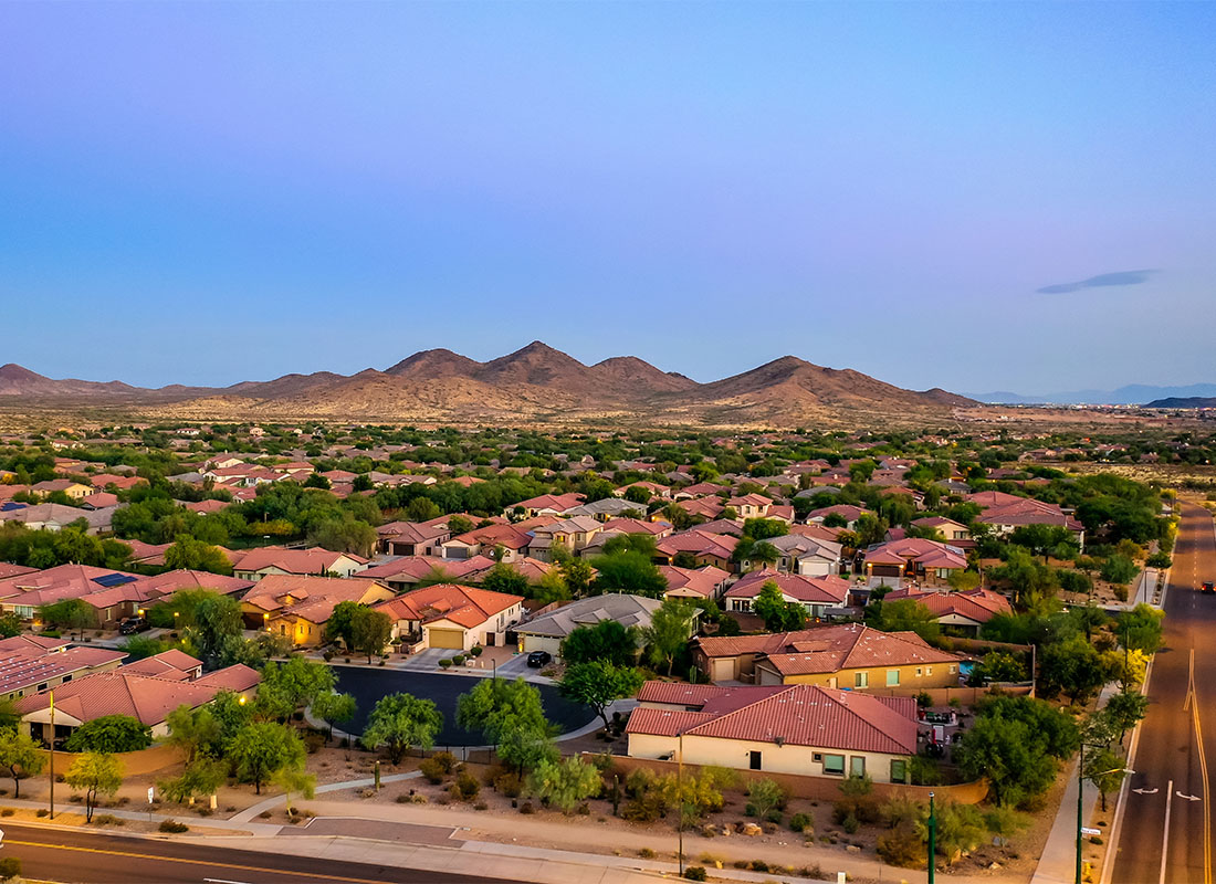 Contact - Aerial View of Homes Surrounded by Green Trees in a Residential Neighborhood in Arizona with Mountains in the Distance Against a Clear Blue Sky